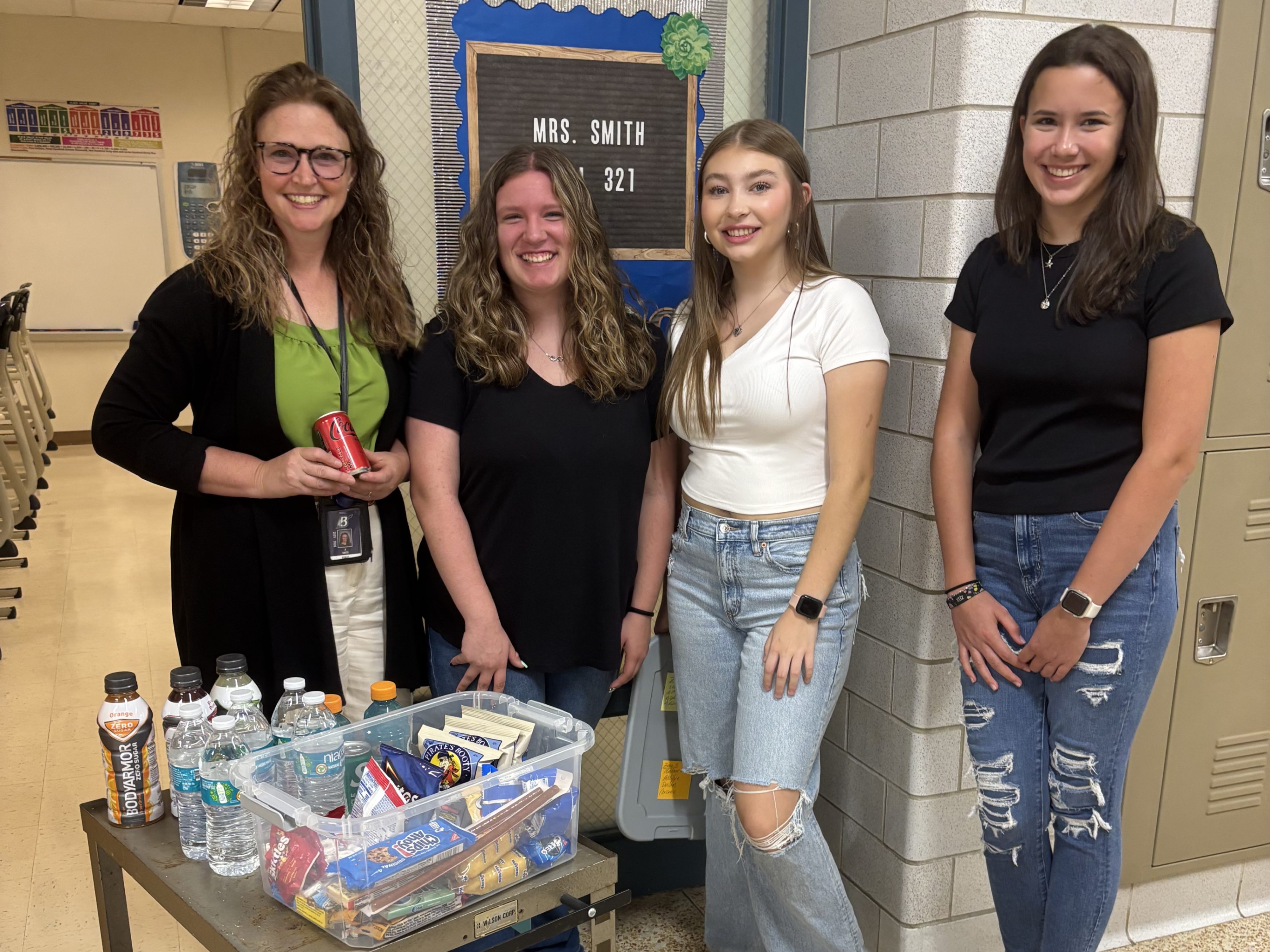 A teacher and students pose for a photo with a snack cart for faculty and staff.